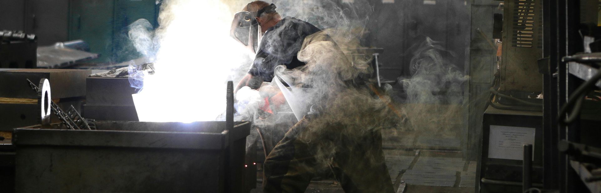 A skilled welder working with intense sparks and smoke in an industrial workshop, showcasing safety and precision.
