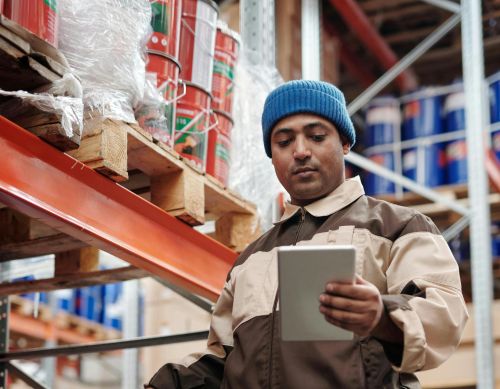Man in warehouse using digital tablet to manage inventory. Indoor workplace shot.