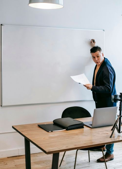 Logistics instructor teaches on a whiteboard using a laptop